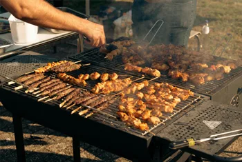 Restaurant chef grilling on commercial charcoal BBQ for professional catering